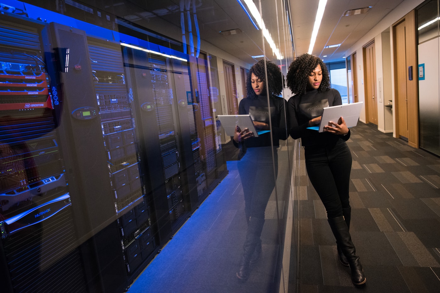 Network operations engineer reviewing a live monitoring dashboard on a tablet beside server racks — AI monitoring feature.